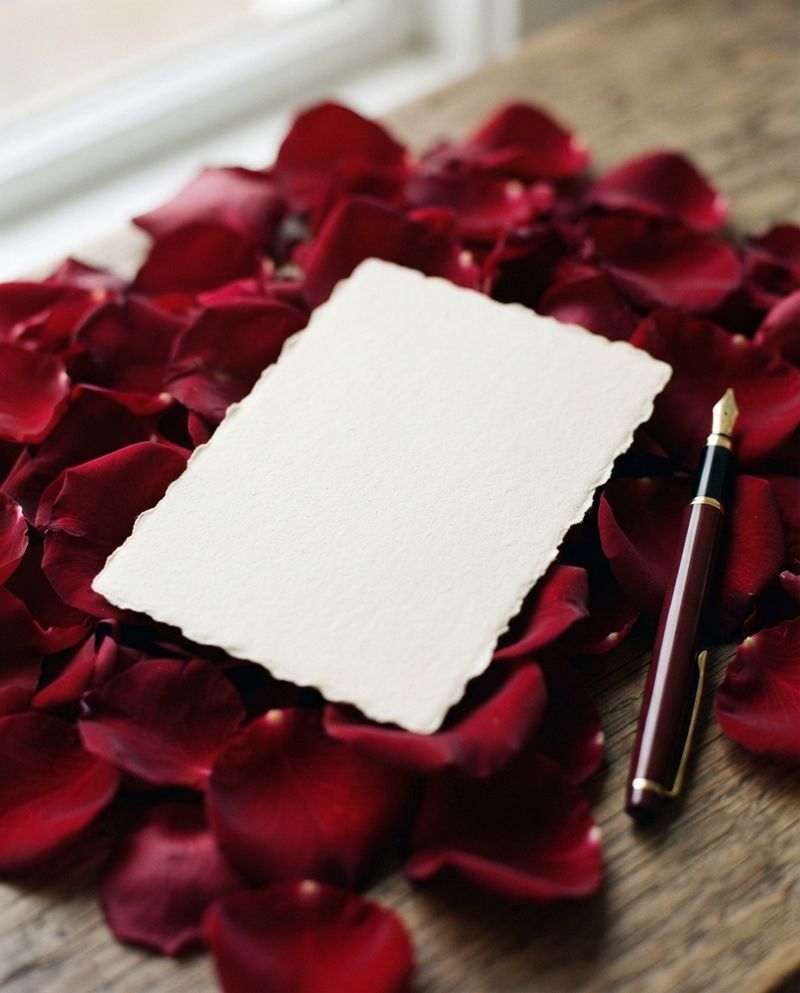 Cartão escrito à mão, pousado sobre pétalas de rosa